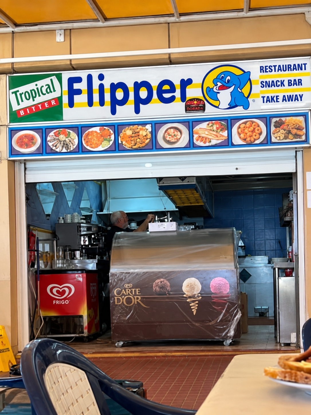 Flipper snack bar before renovation, with the old counter, display freezer and tiled kitchen opening