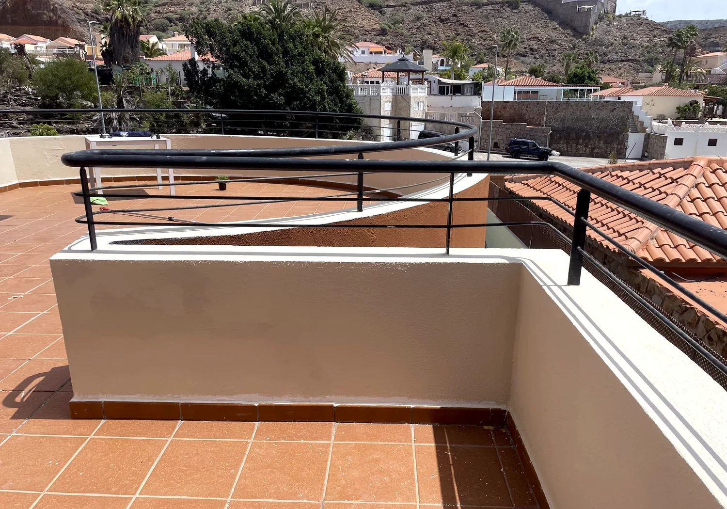 Terracotta-tiled terrace with rendered parapet walls and black metal railings